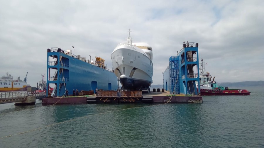 A hull on a floating dock during launch at a shipyard.